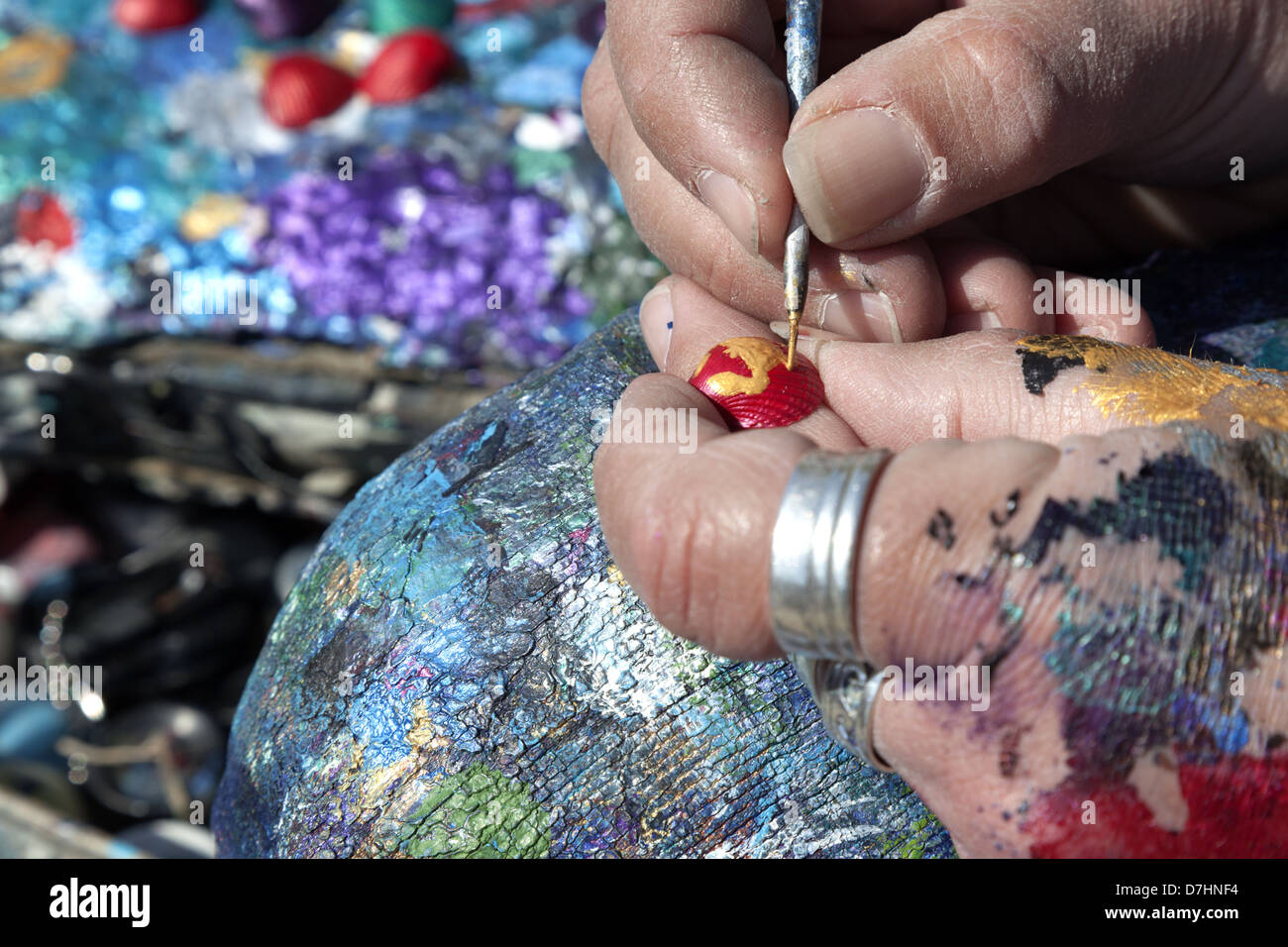 La peinture de l'artiste petit sea shell. Close up of fingers. Banque D'Images