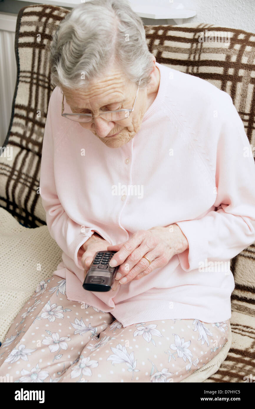 Femme âgée à l'aide d'un gros bouton spécialisées téléphone appelant le 111 ligne d'aide des conseils médicaux d'urgence en raison de se sentir malade Banque D'Images