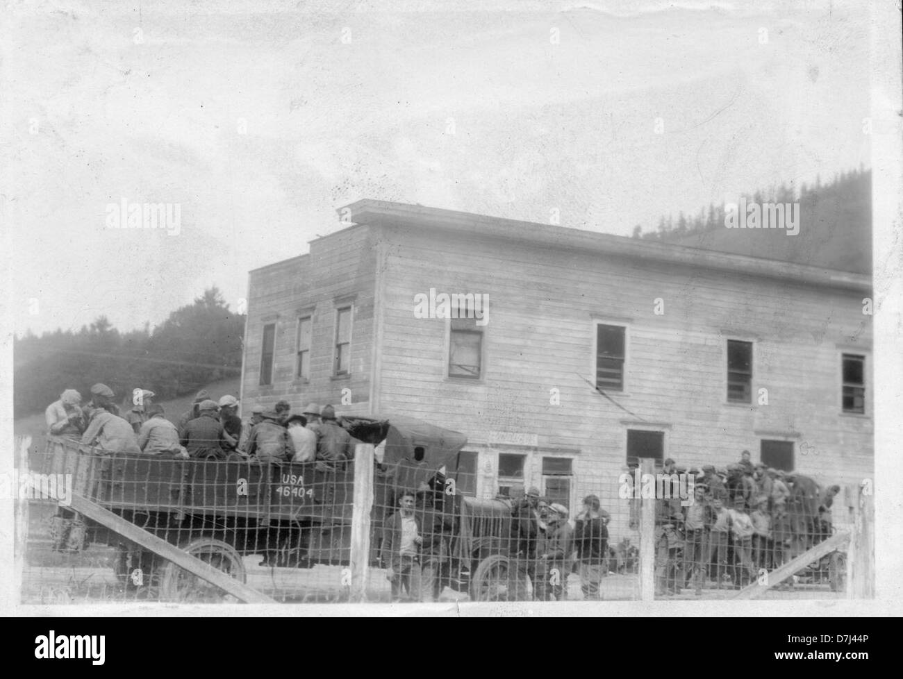 Cette photographie en noir et blanc capture des personnes rassemblées à l'extérieur d'un magasin de campagne vers 1935. L’image offre un aperçu de la vie rurale et des dynamiques sociales de l’époque. Banque D'Images