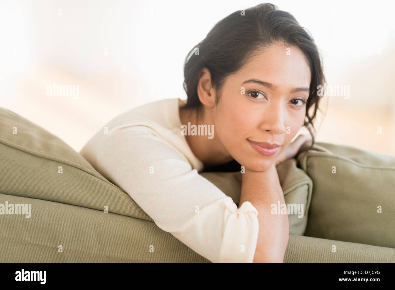 Portrait of young woman sitting on couch Banque D'Images