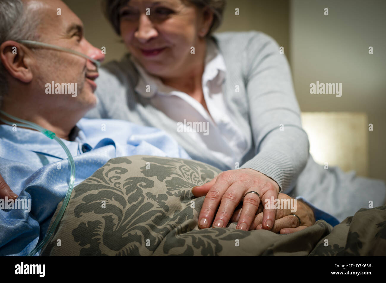 Vieux couple holding hands homme malade au lit Banque D'Images