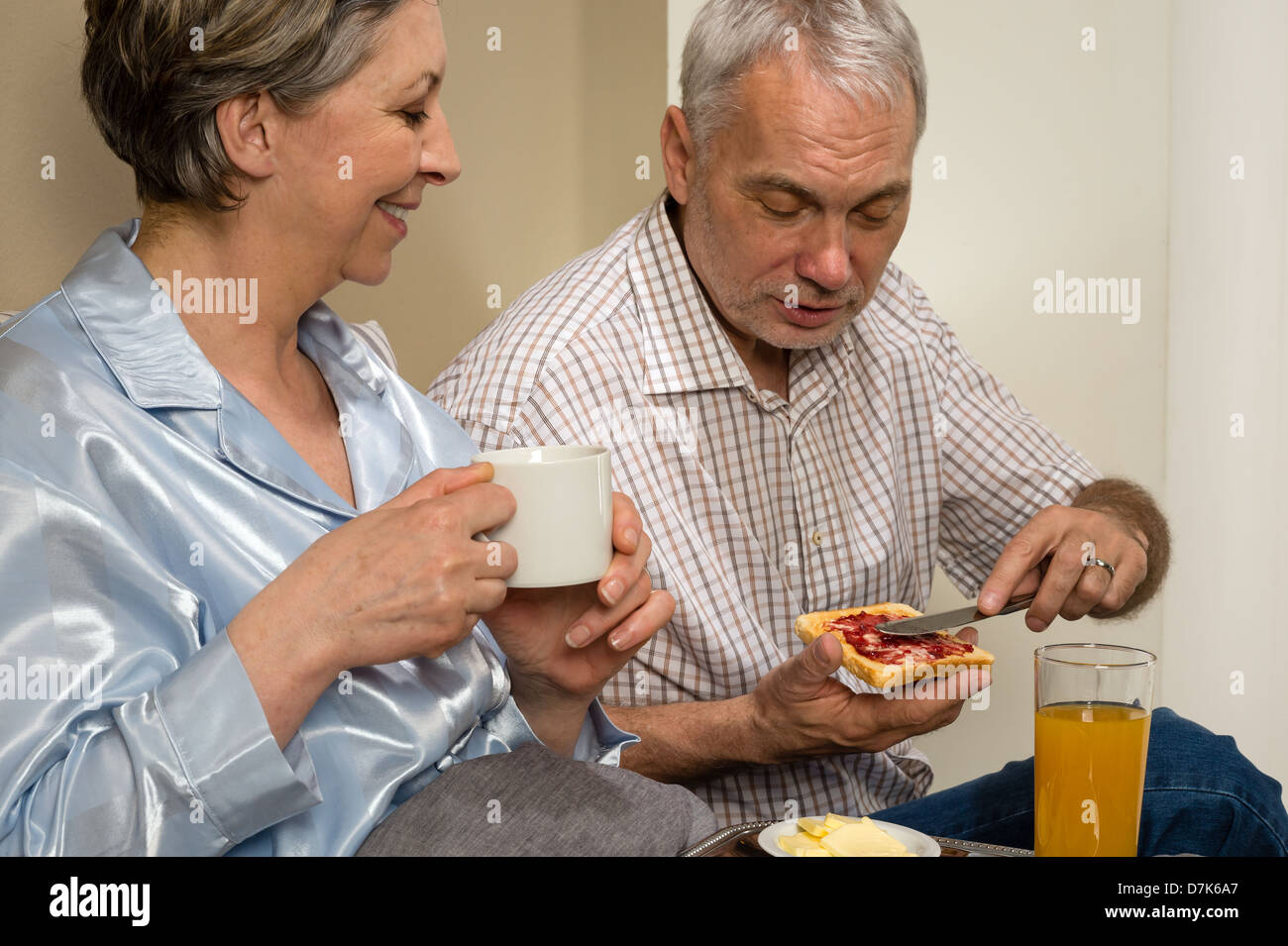 Couple de personnes âgées de manger un petit-déjeuner romantique together in bed Banque D'Images