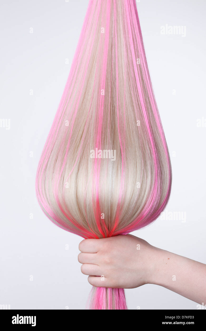 Human hand holding cheveux blonds avec faits saillants rose against white background, Close up Banque D'Images