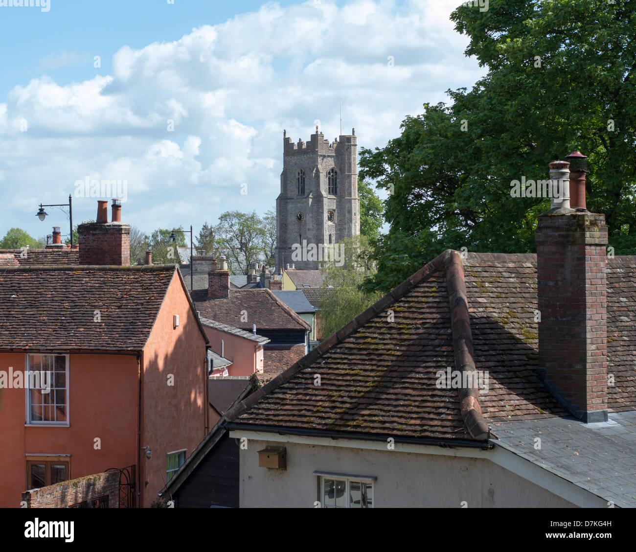 La tour de l'église de Saint tous à Sudbury, Suffolk, Angleterre, avec de vieux toits de maison au premier plan. Banque D'Images
