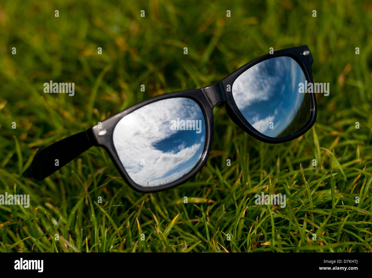 Beau ciel bleu reflété dans une paire de lunettes wayfarer en miroir pour représenter l'été Banque D'Images