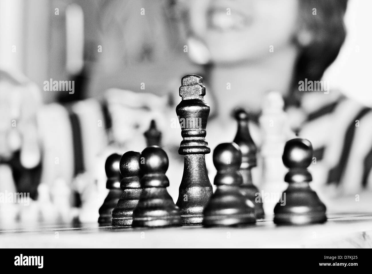 Des pièces d'échecs sur un échiquier avec un petit garçon dans l'arrière-plan Banque D'Images