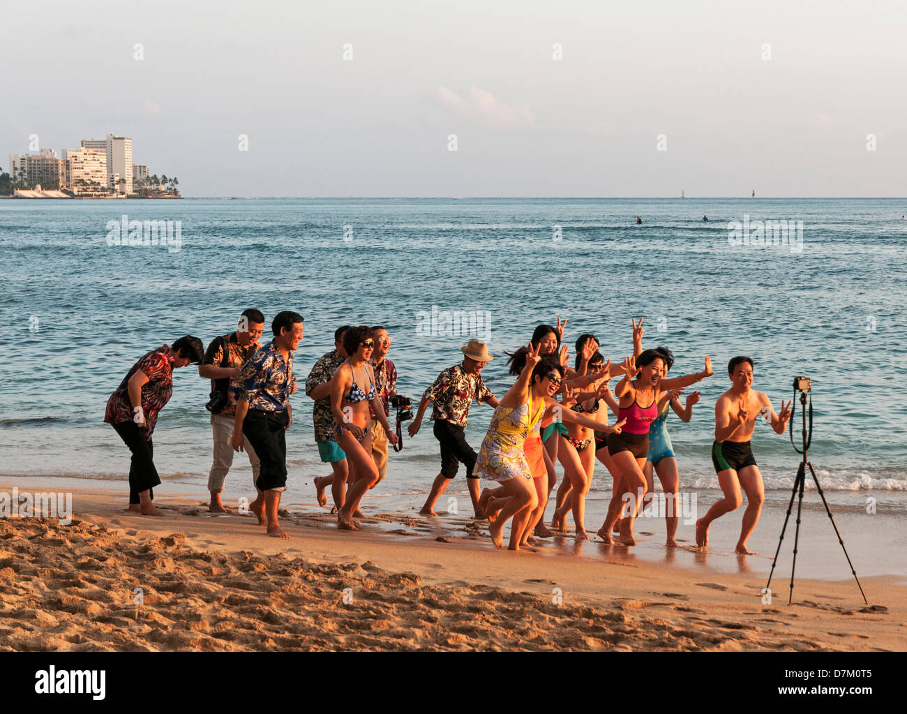 Un groupe de touristes chinois sur la plage de Waikiki faisant un heureux enregistrement vidéo de leur voyage à Hawaii. Banque D'Images