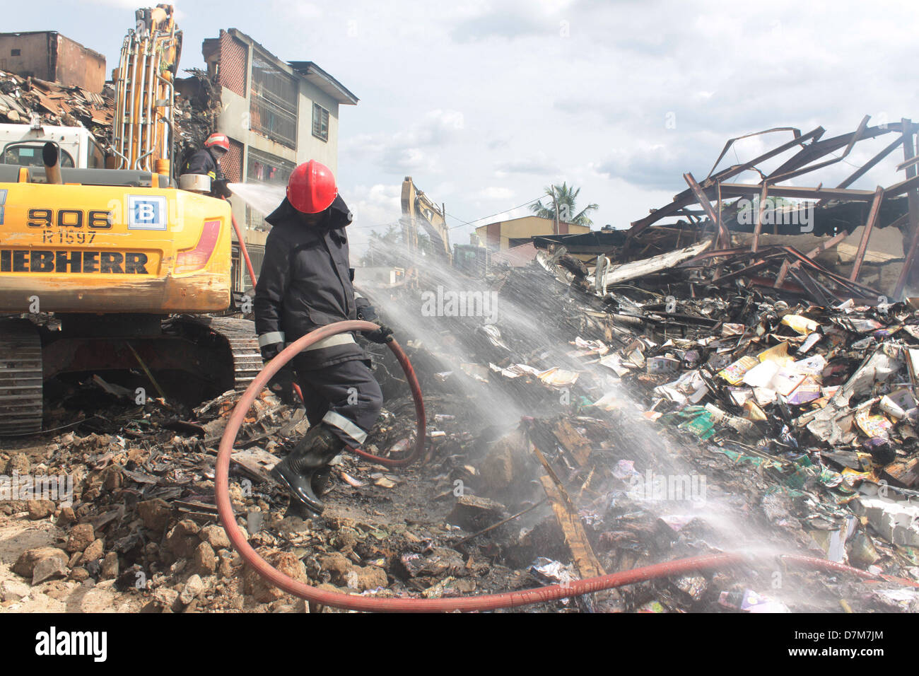 Les pompiers éteindre les couver à l'emplacement d'un récent accident d'avion à la périphérie de Lagos, Nigeria. Banque D'Images