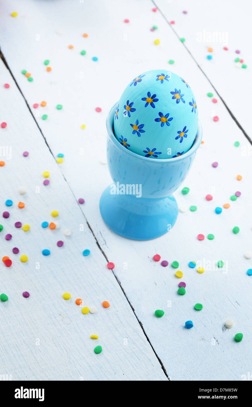Oeufs de Pâques peints bleu sur blanc table entre des sprinkles sucre Banque D'Images