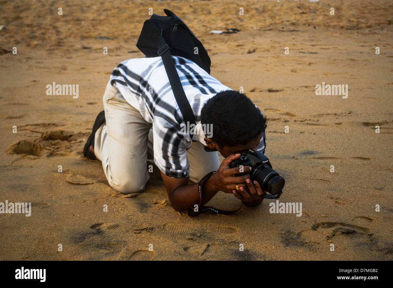Un jeune photographe en attente pour le crabe pour venir jusqu'à obtenir un bon coup Banque D'Images