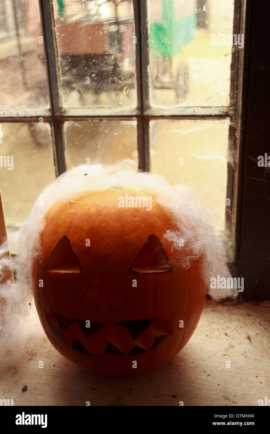 Un citrouilles au visage sculpté et web s/n placé sur une fenêtre pour l'halloween. Banque D'Images