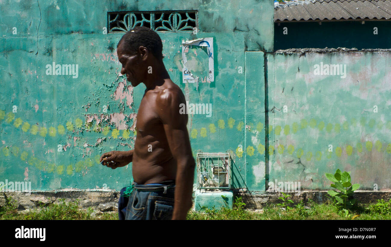 Homme marchant dans l'avant du mur vert. Ville, île de Baru Baru, près de Carthagène, Colombie Banque D'Images