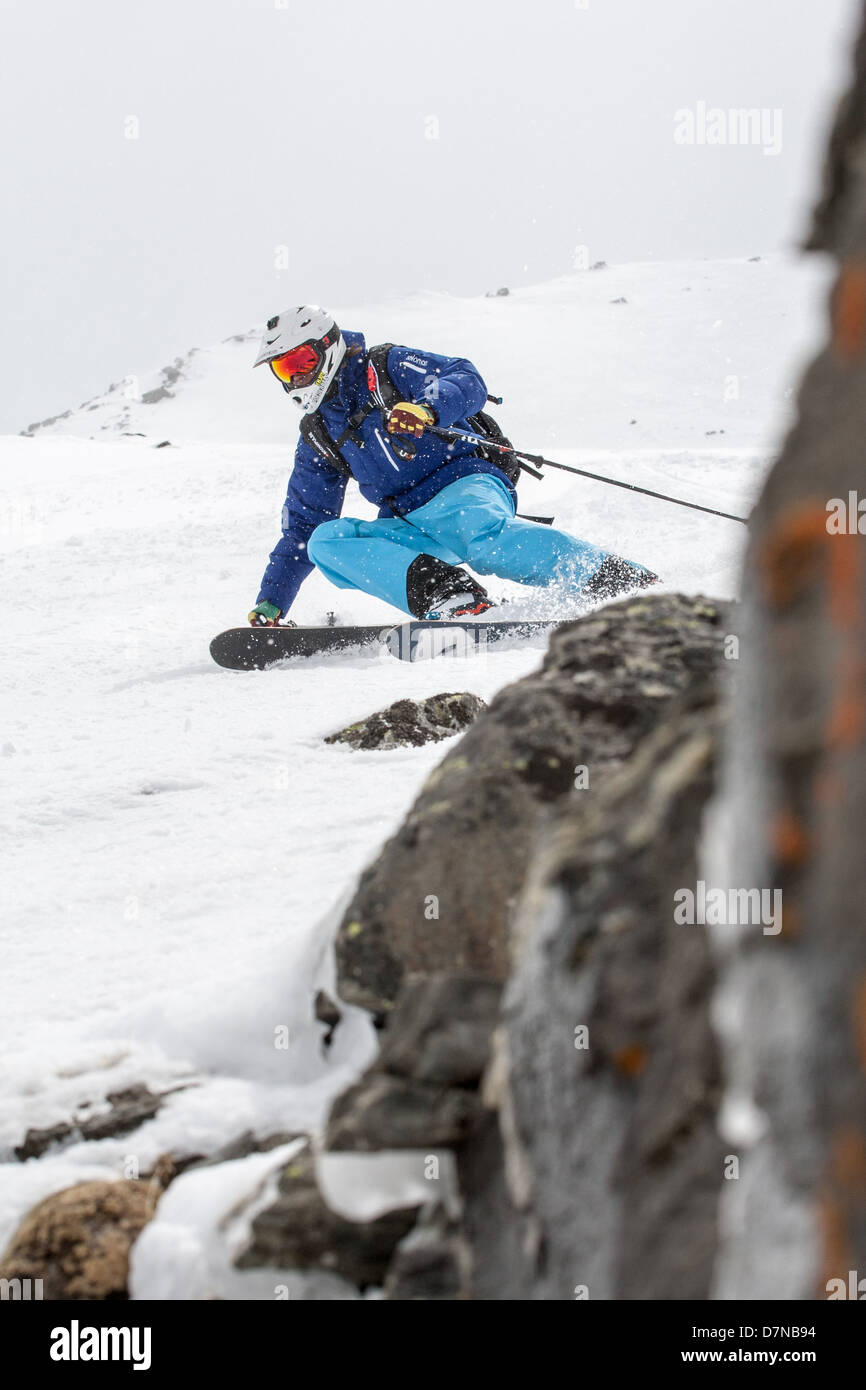 Skieur Freeride tournant près d'un rocher Banque D'Images