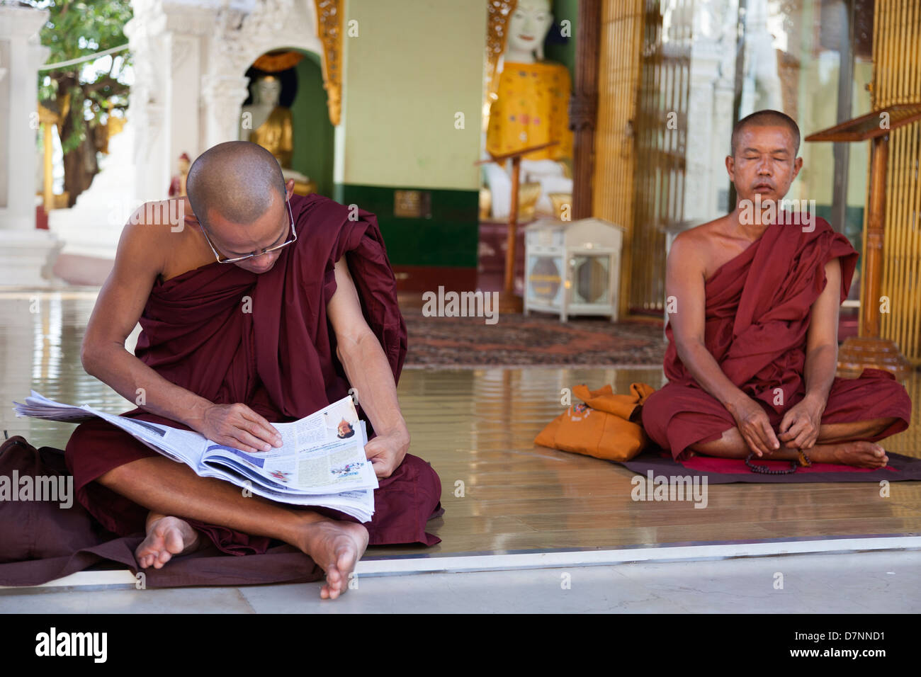 Deux moines - l'un méditant et un lire un journal - à la pagode Shwedagon à Yangon, Myanmar 2 Banque D'Images