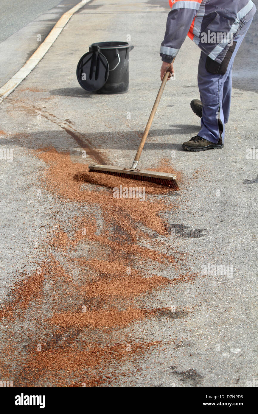 Nettoyage d'entretien des routes une trace d'huile avec un balai Banque D'Images