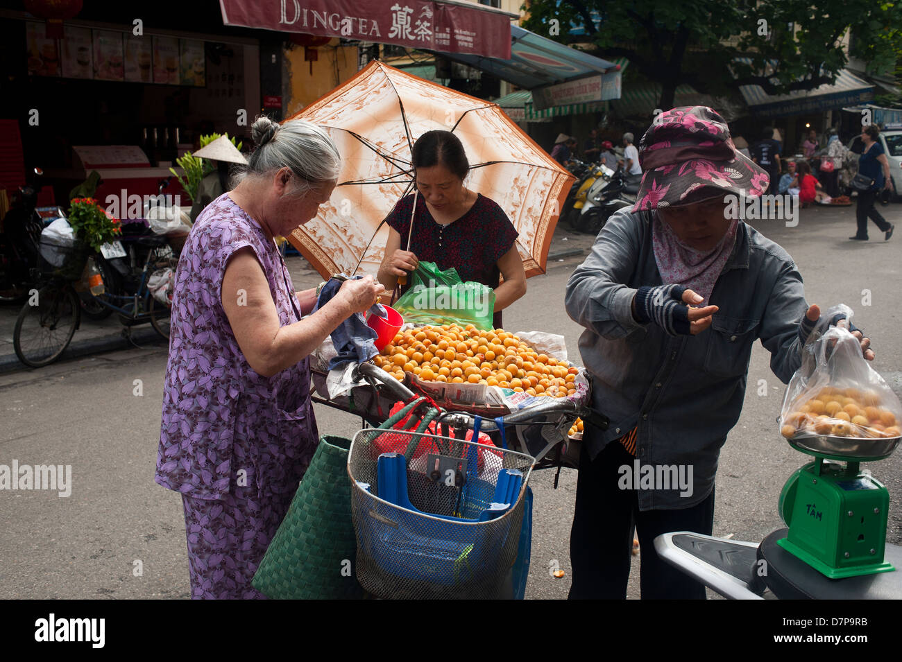 Hanoi Vietnam femme vendre des boules de sésame dans la rue : un vendeur offre des boules de sésame fraîchement frites (bánh Cam / jian dui), une collation sucrée populaire Banque D'Images