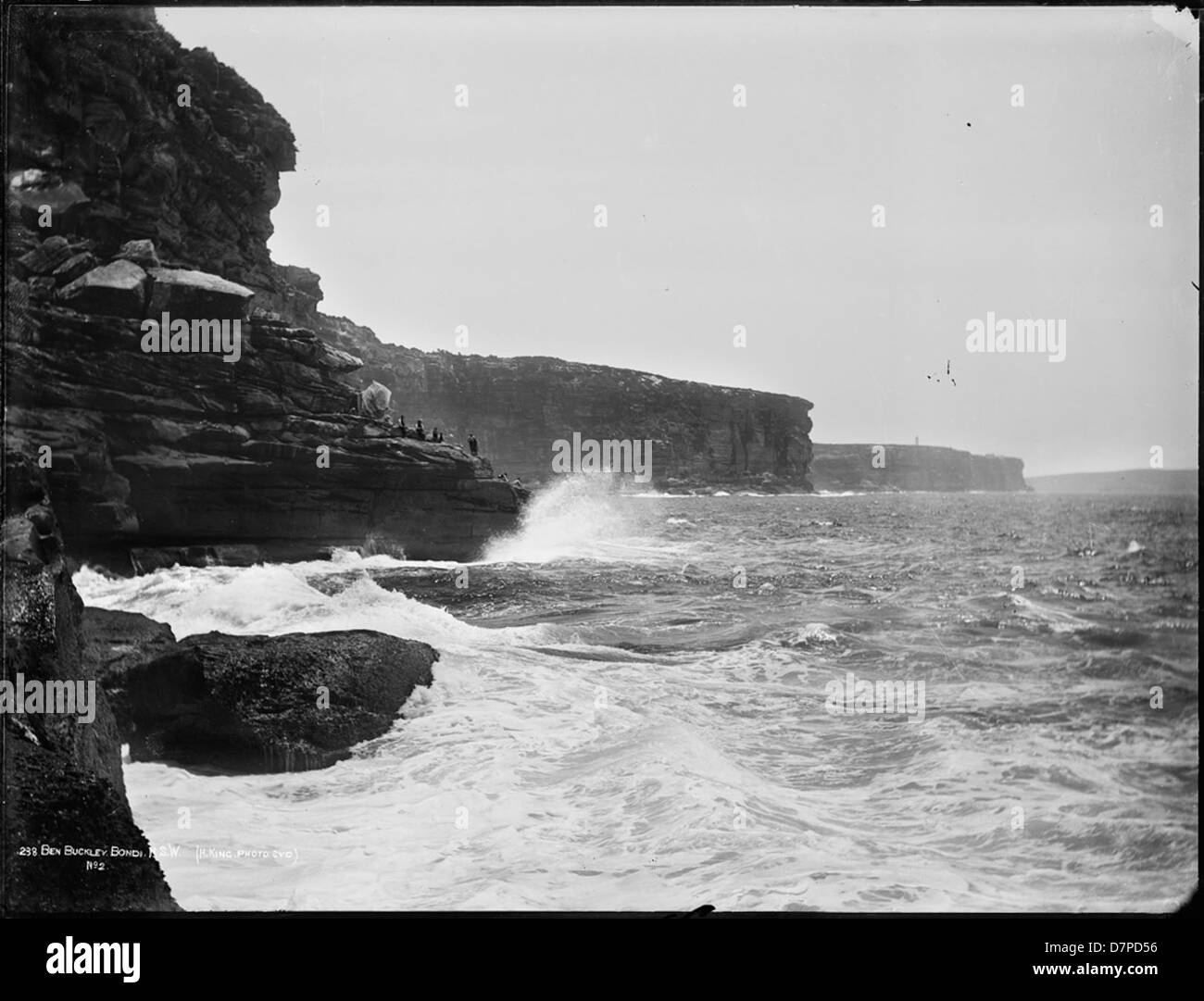 Cette photographie en noir et blanc capture le paysage spectaculaire de Ben Buckler, Bondi, Nouvelle-Galles du Sud, avec les falaises accidentées et les vagues qui s'écrasent. L'image montre les puissantes forces de la nature le long du littoral australien. Banque D'Images