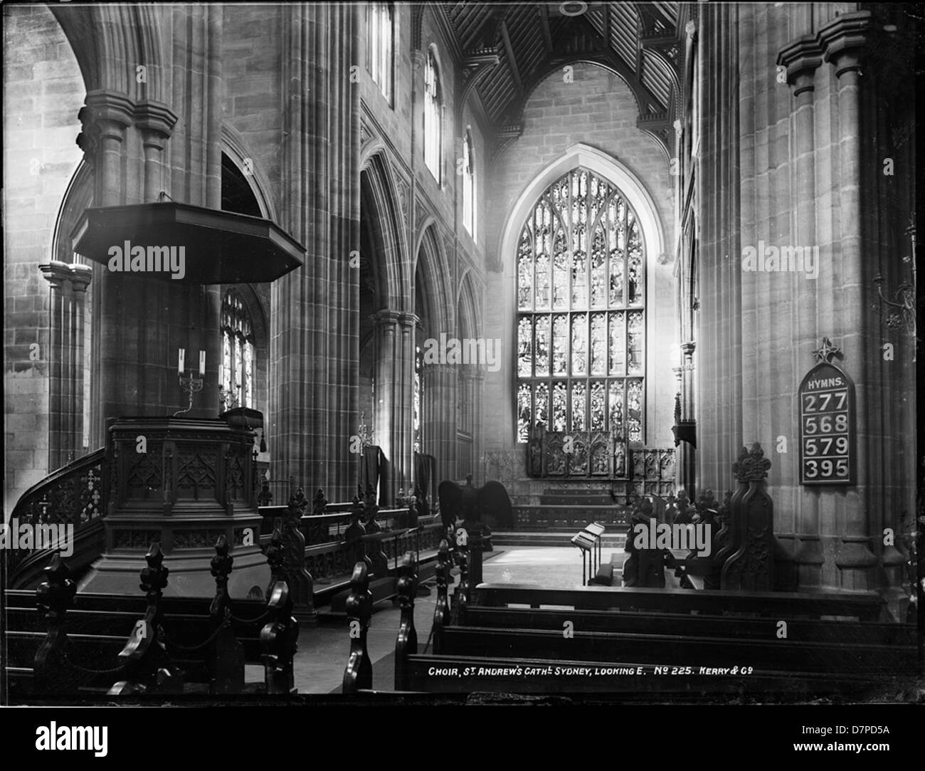 Cette photographie historique en noir et blanc capture le chœur de la cathédrale St Andrew de Sydney, en Australie, regardant vers l'est. La cathédrale, un exemple emblématique de l'architecture néo-gothique, présente son magnifique plafond en bois, ses bancs et ses vitraux. Banque D'Images