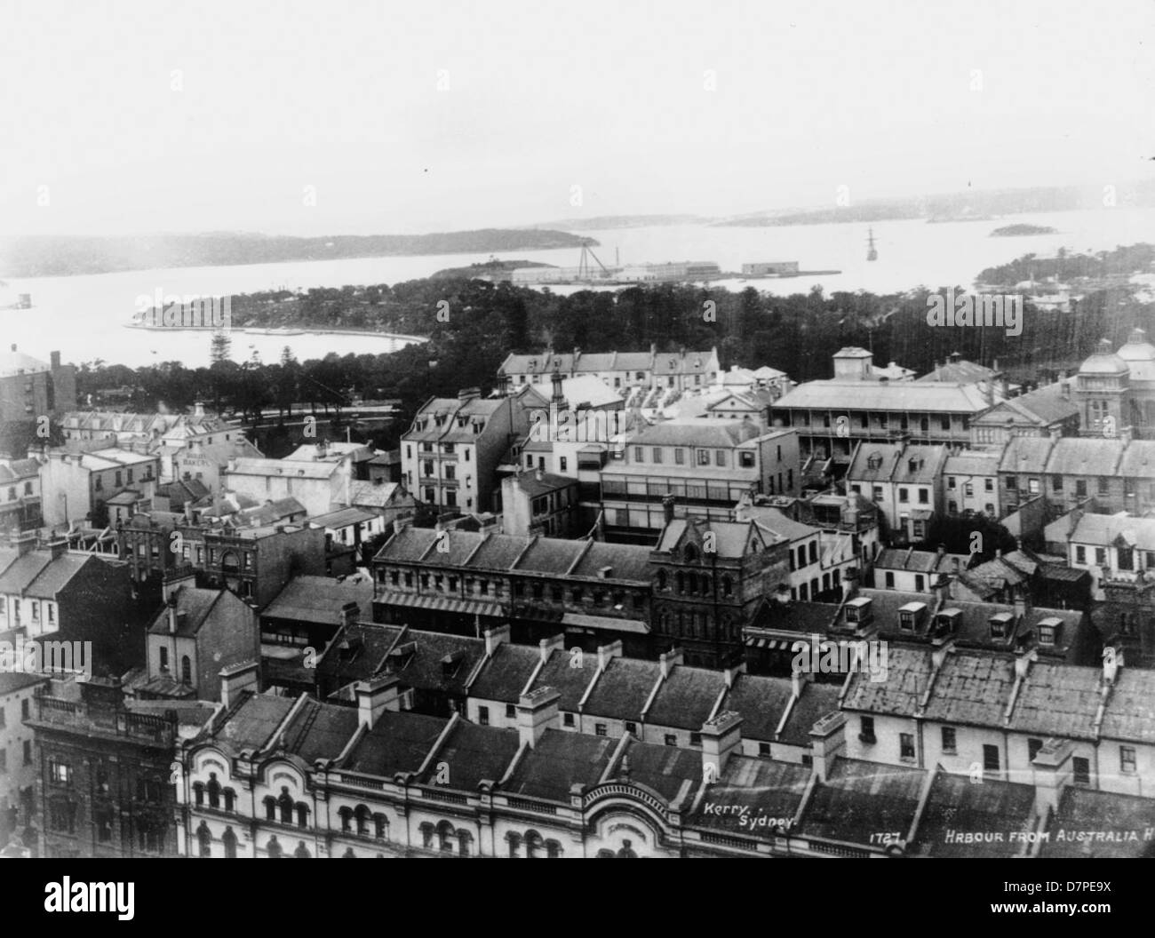 Cette photographie offre une vue sur le port de Sydney prise depuis le célèbre Australia Hotel. L'image capture l'immense port, avec ses eaux emblématiques, ses bateaux et l'animation des gratte-ciel de Sydney. La photographie souligne le paysage urbain et l'activité maritime caractéristique de la zone portuaire. Banque D'Images