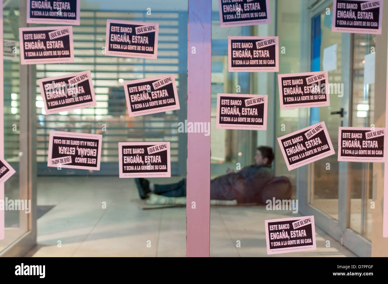 Un sans-abri relève au guichet automatique après une manifestation au cours de laquelle ils ont collé des affiches qui peuvent être lus, ce chèque bancaire et escroquerie Banque D'Images