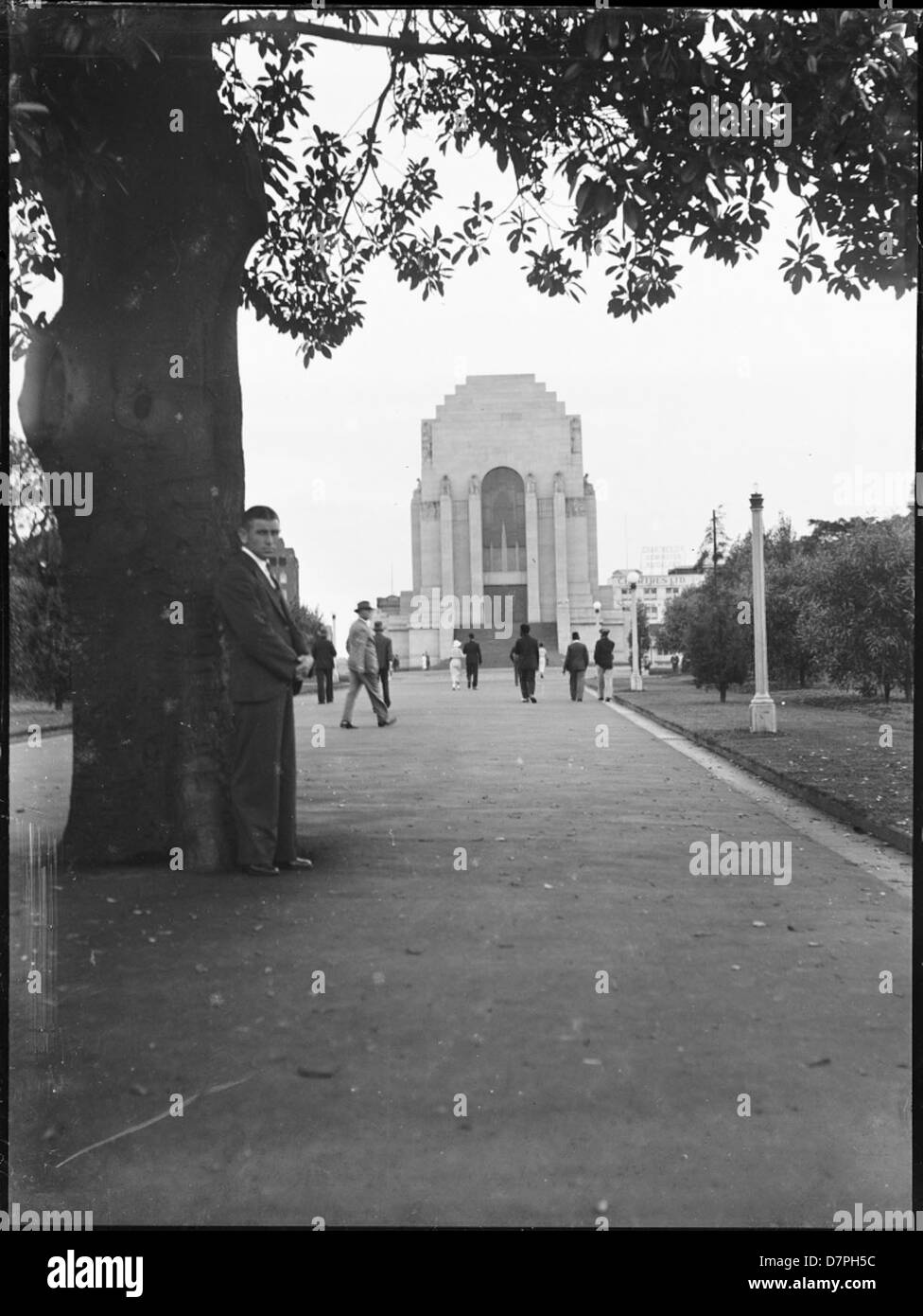 Homme posant en vertu de l'arbre en face de l'Anzac War Memorial dans Hyde Park, Sydney Banque D'Images