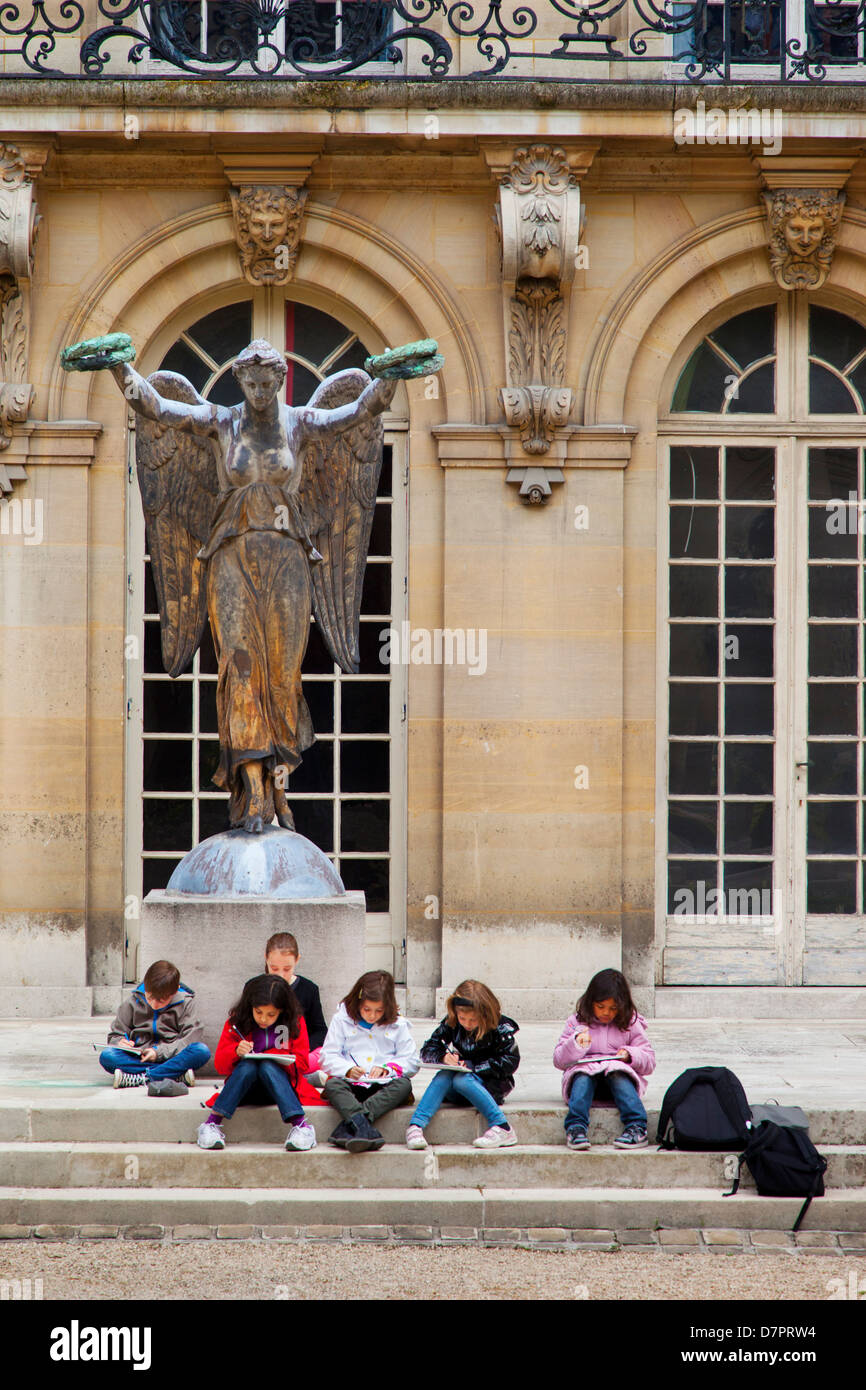 Jeunes écoliers en voyage sur le terrain de l'art à l'Hôtel Carnavalet, créant des dessins dans le Marais, Paris, France Banque D'Images