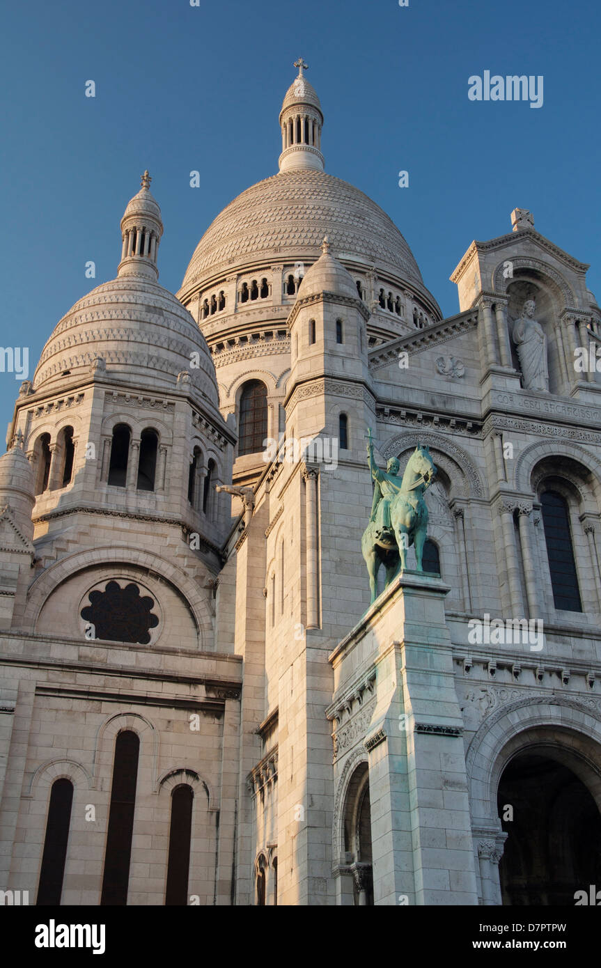 La façade et les imposantes coupoles blanches de la basilique d'Sacra-Coeur à Montmartre. Au-dessus du portique, est une statue du roi Saint Louis. Paris, France. Banque D'Images