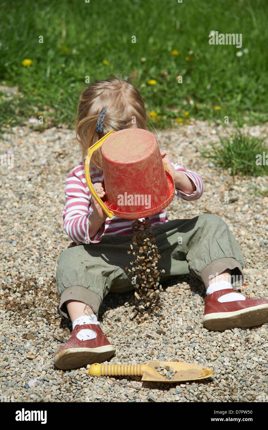 Blonde yeux bleu enfant bébé fille 2 ans jouant avec des pierres et des cailloux en plein air sur l'aire de jeux Banque D'Images