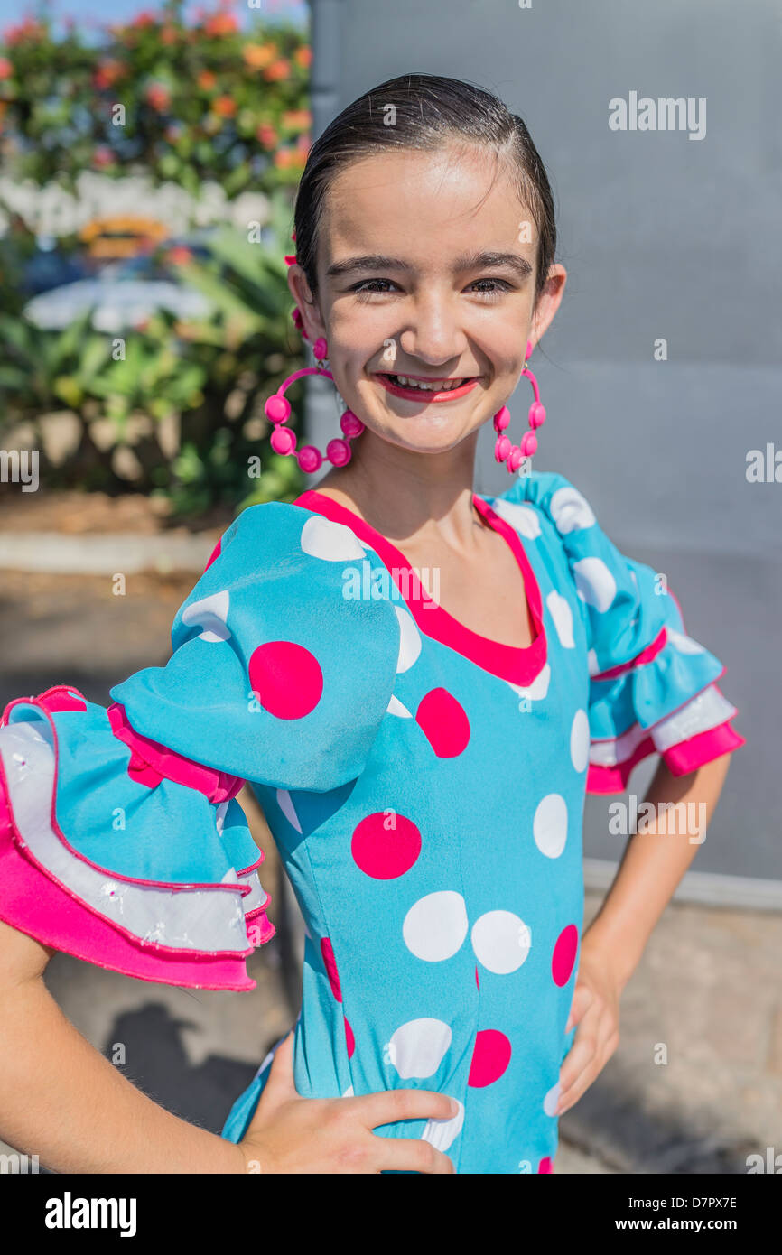 Un enfant dans son danseur hispanique de l'adolescence tôt pose dans son costume de danse flamenco traditionnel coloré, robe, boucles d'oreilles et d'un sèche avant. Banque D'Images