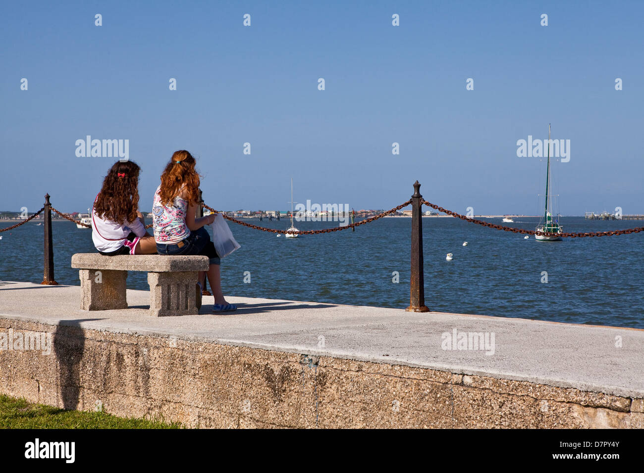 Deux jeunes femmes sont assises sur un banc avec vue sur la baie de Matanza à Saint Augustine, Floride Banque D'Images