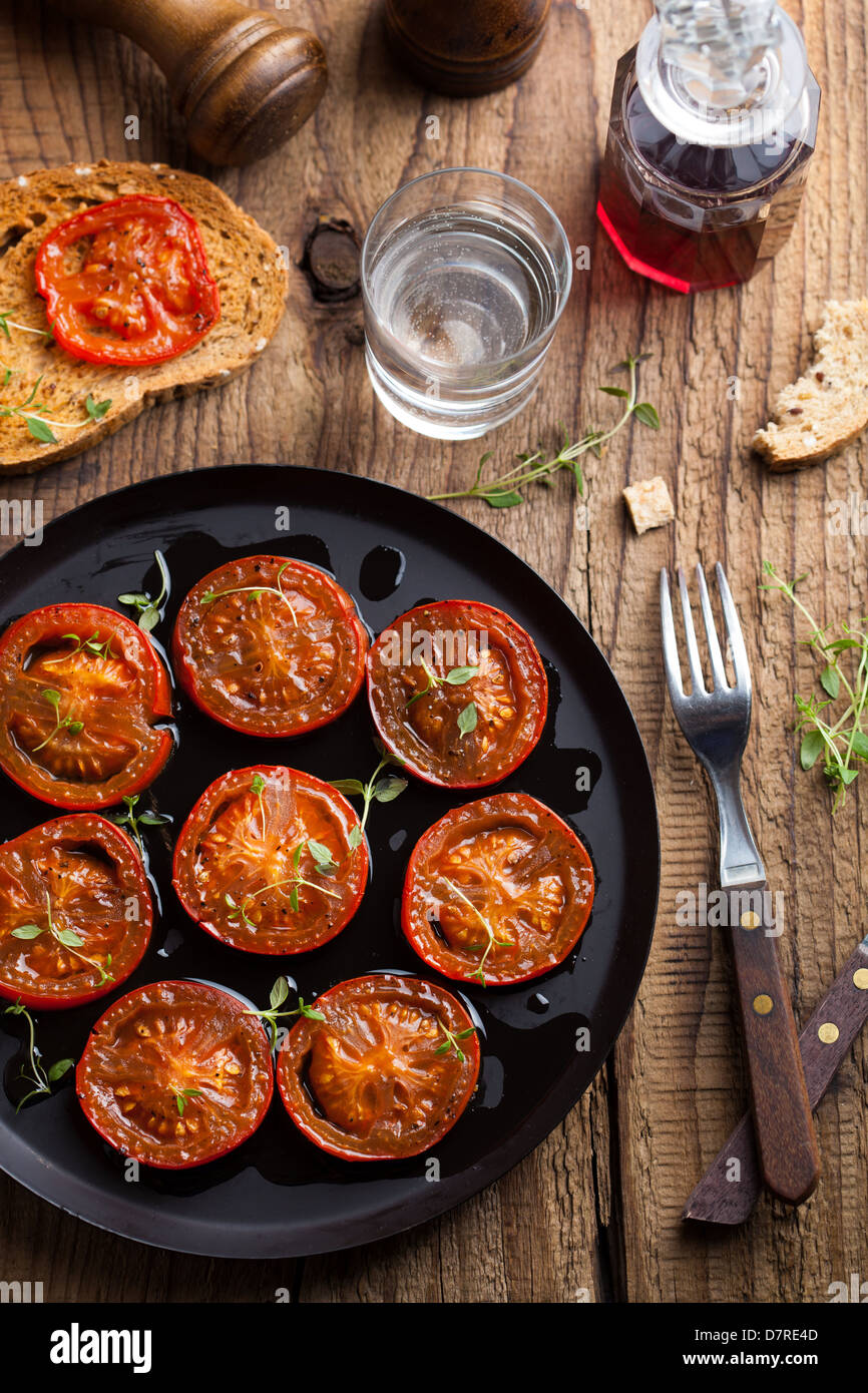 Les tomates cuites au four avec des herbes et d'huile d'olive Banque D'Images