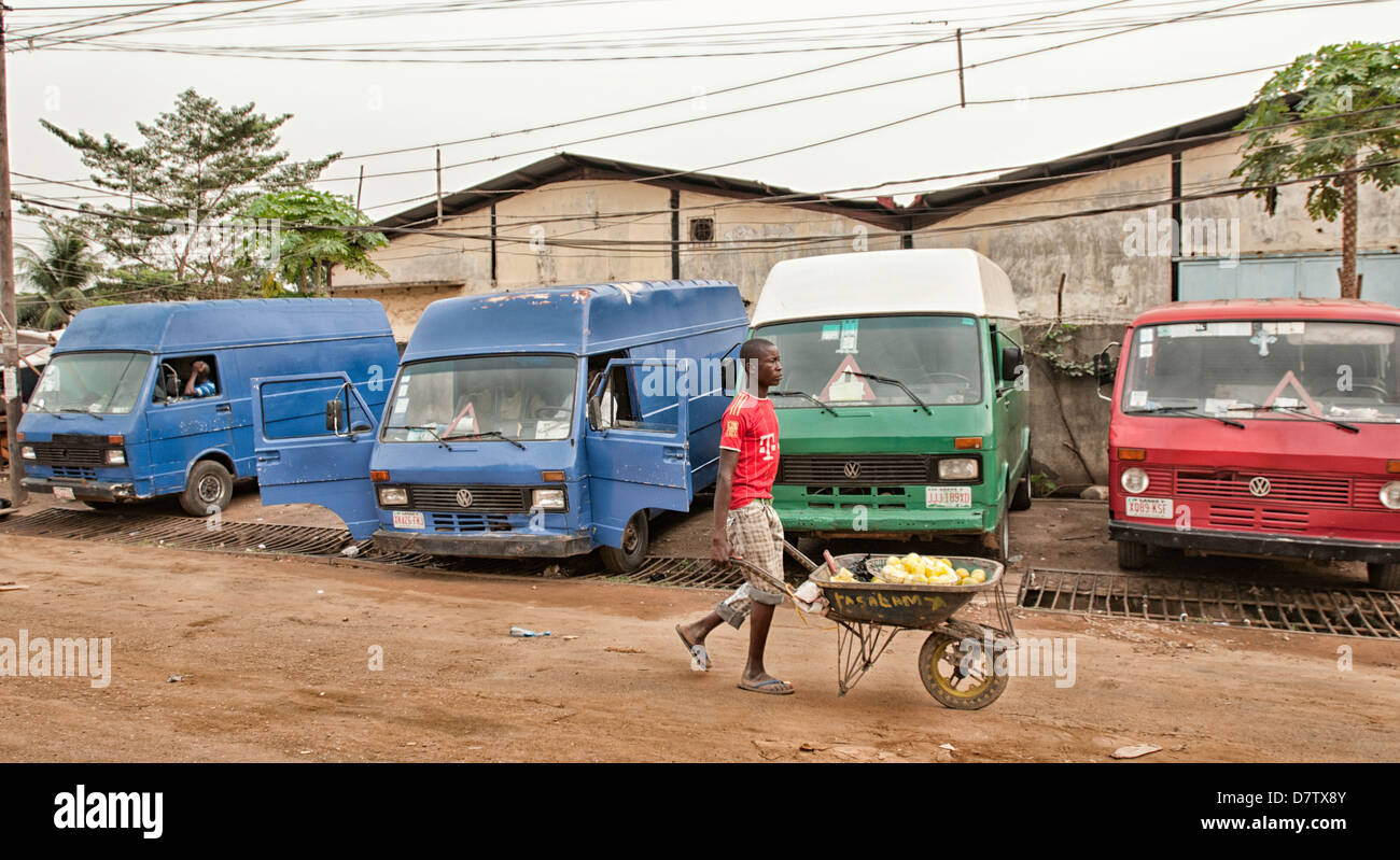 Un garçon tire sa brouette dans la rue de Lagos. Banque D'Images