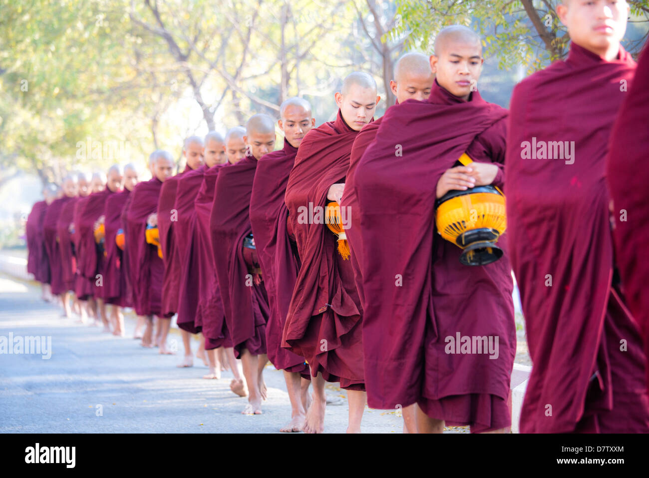 Les moines bouddhistes de marcher le long de la route pour recueillir des aumônes, près de Shwezigon Paya, Nyaung U, Bagan, Birmanie Banque D'Images