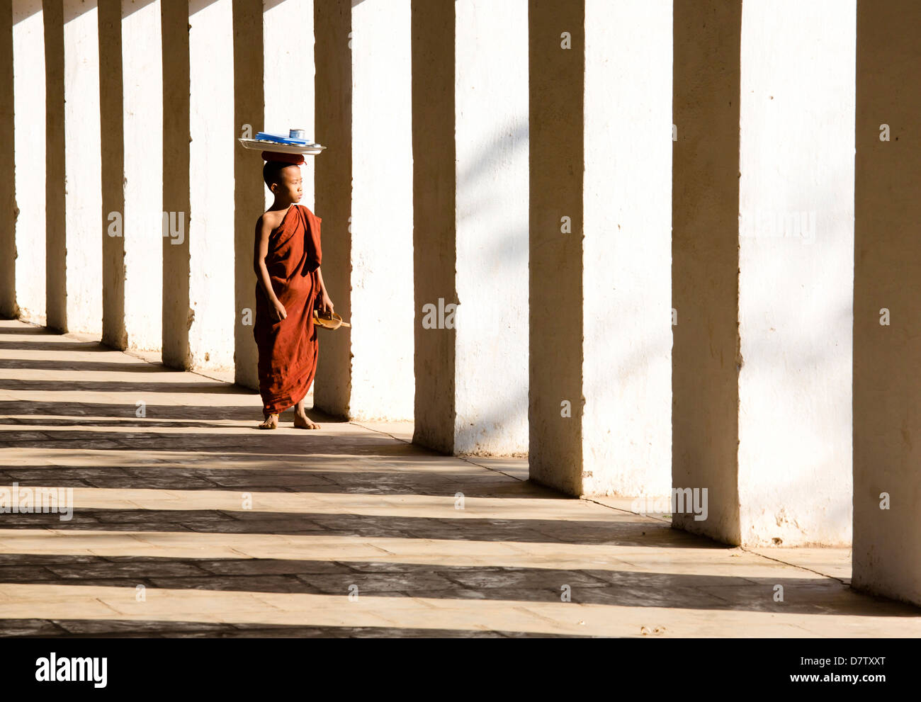 Moine Bouddhiste Novice debout dans l'ombre de colonnes à Shwezigon Paya, Nyaung U, Bagan, Birmanie Banque D'Images