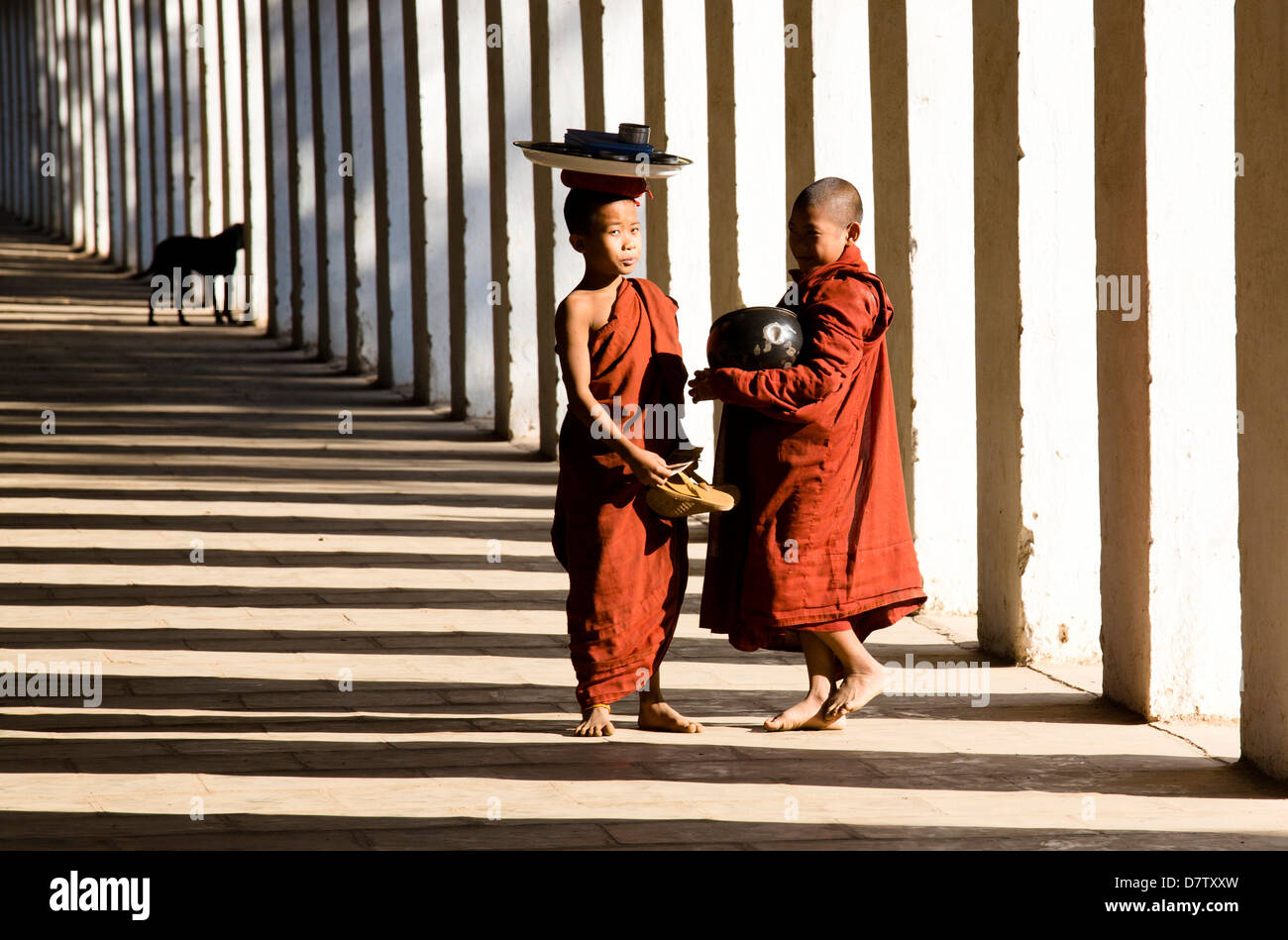 Les moines bouddhistes débutants recueillir l'aumône, debout dans l'ombre de colonnes à Shwezigon Paya, Nyaung U, Bagan, Birmanie Banque D'Images