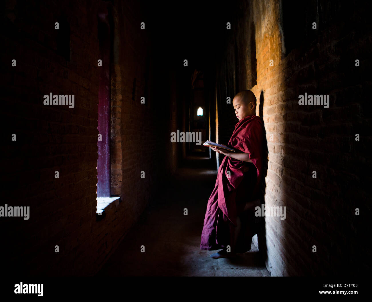 Moine Bouddhiste Novice écritures bouddhistes de lecture à la lumière d'une fenêtre dans l'un des nombreux temples de Bagan, Birmanie Banque D'Images