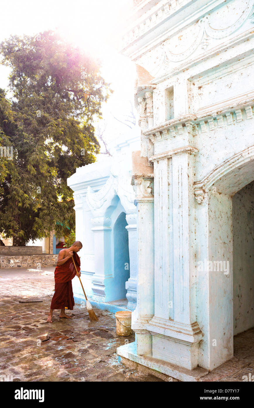 Le moine bouddhiste à l'extérieur d'un pavage de nettoyage petit temple près du célèbre pont en teck U Bein, Amarapura, près de Mandalay, Birmanie Banque D'Images