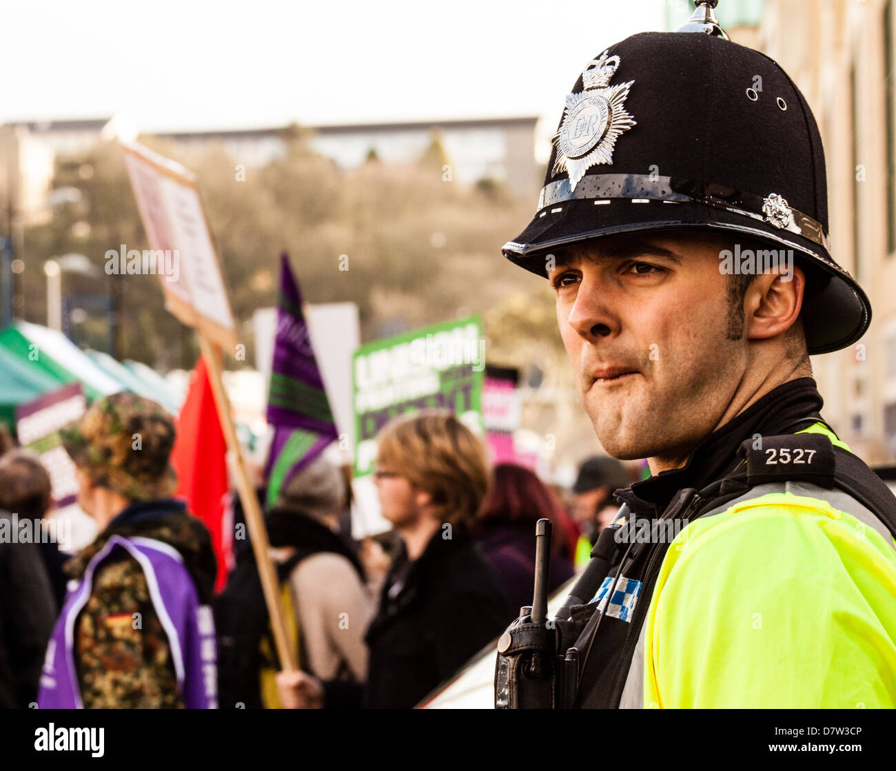 Les gens protestent contre la coalition gouvernement coupe comme un policier regarde sur. Banque D'Images