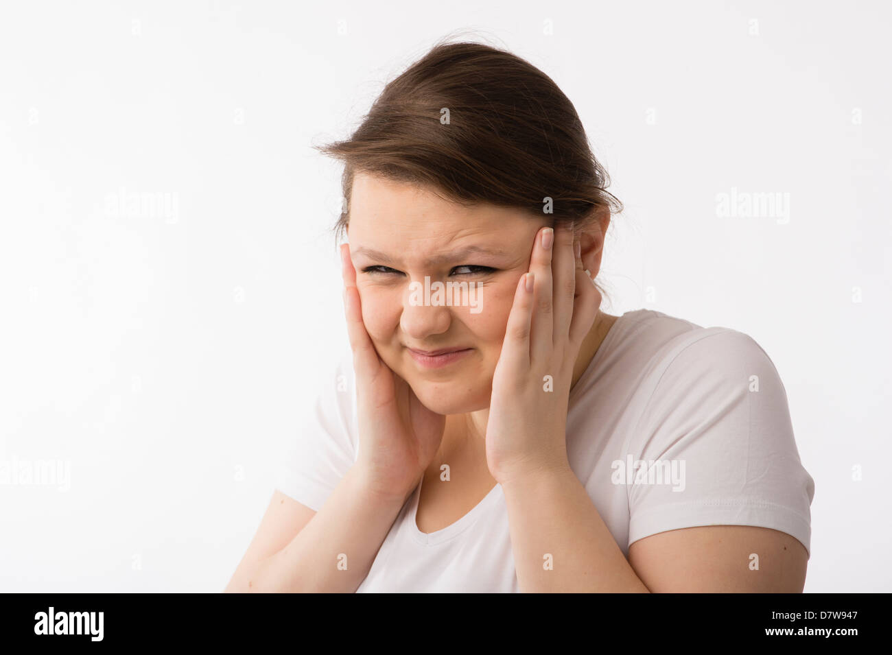 Une jeune brunette young Caucasian girl couvrant ses oreilles pour garder hors le bruit fort ou avec un mal de tête Banque D'Images