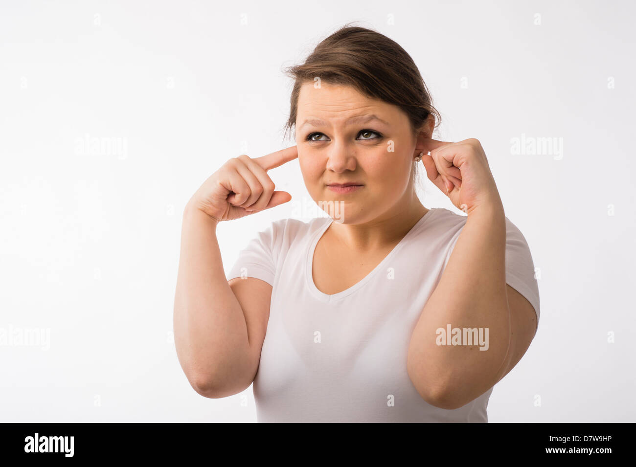 Une jeune brunette young Caucasian girl avec ses doigts dans ses oreilles de tenir à l'écart du bruit retentit Banque D'Images