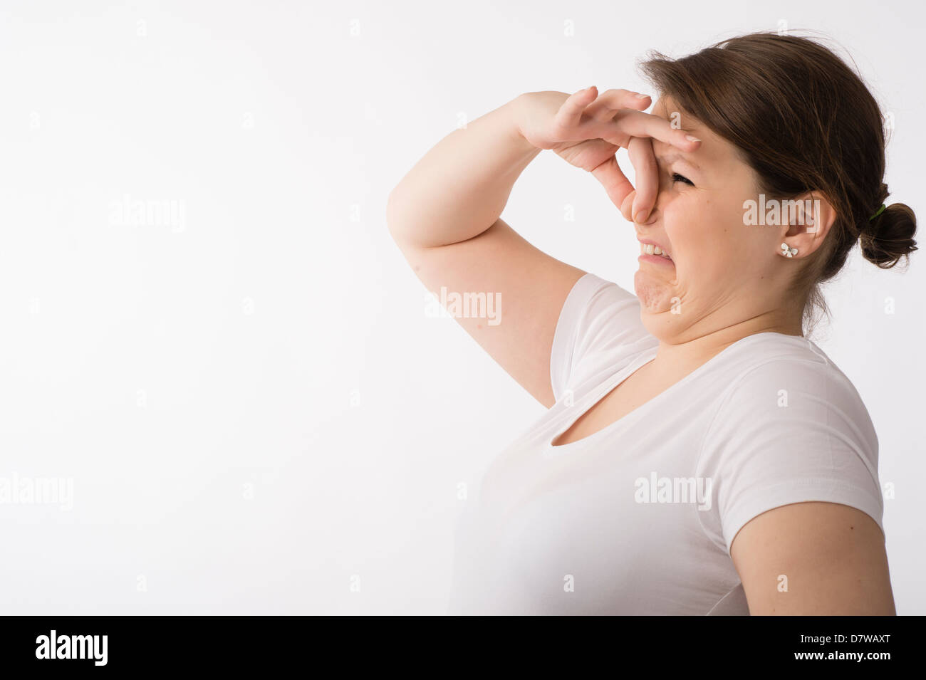 Une jeune brunette young woman holding pincer son nez pour tenir à une mauvaise odeur odeur Banque D'Images