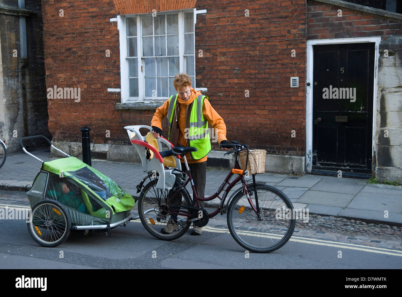 Remorque de poussette Childs attachée à un vélo. Père portant des vêtements de haute visibilité une veste de sécurité, s'occupant de son vélo. Oxford Oxfordshire Royaume-Uni années 2013 2010 Royaume-Uni HOMER SYKES Banque D'Images