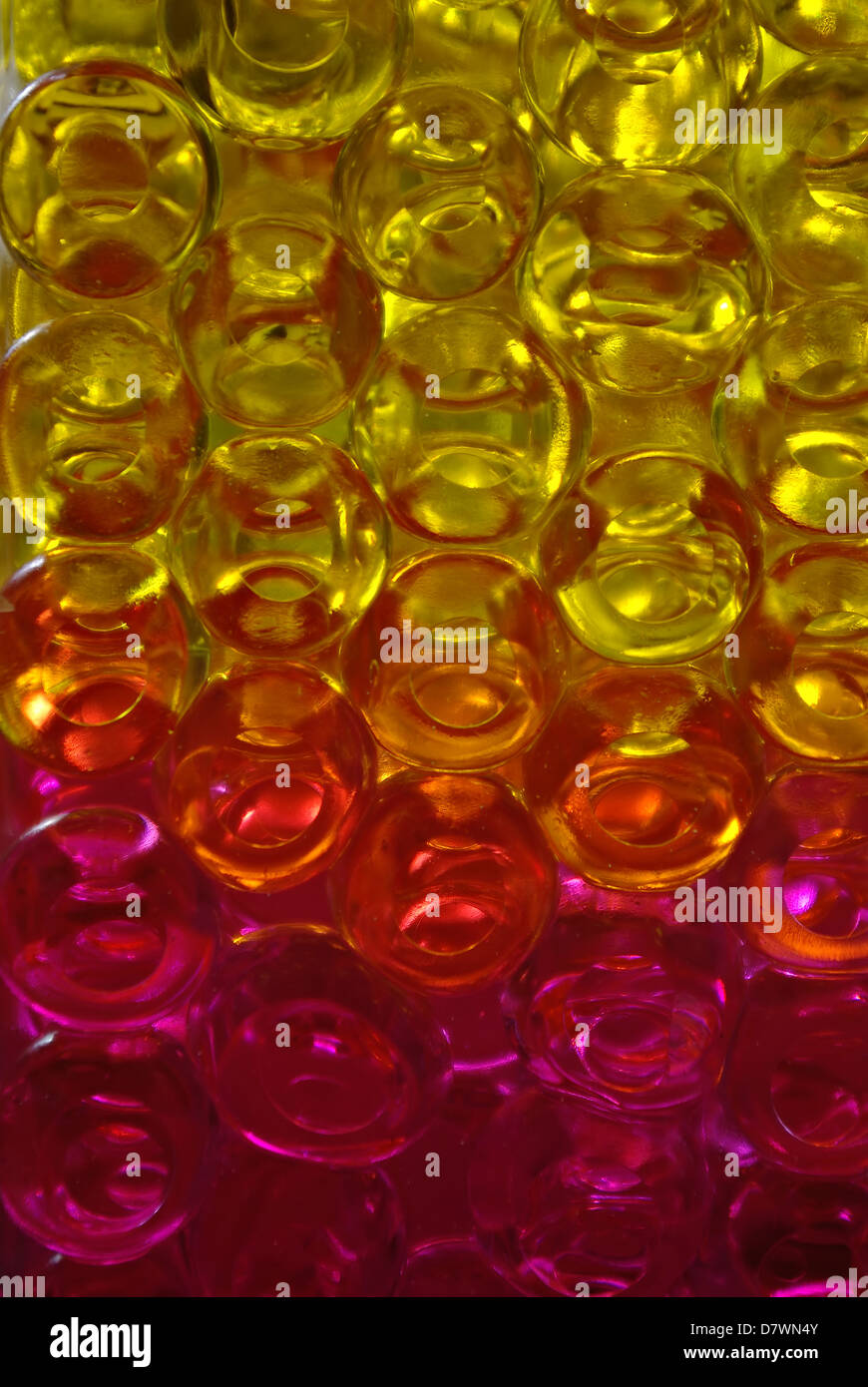 Jaune, orange et rose jelly transparent billes en verre vase avec lumière arrière. Banque D'Images