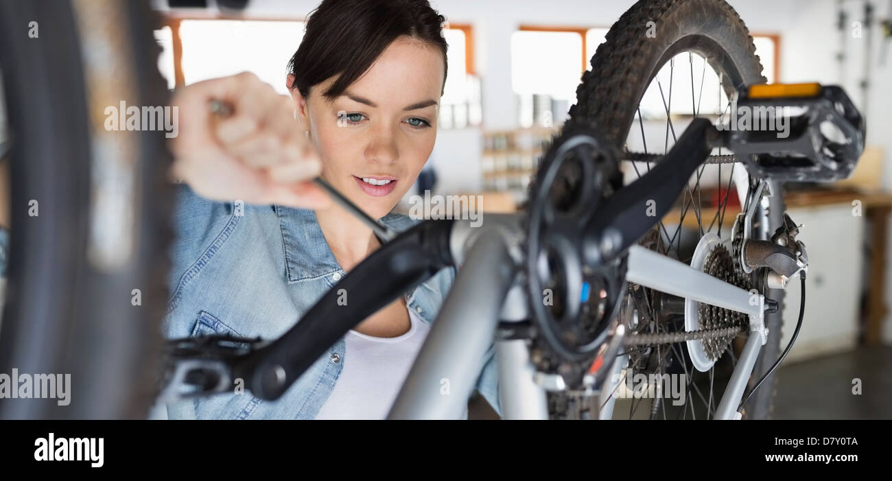 Woman working on bicycle in shop Banque D'Images