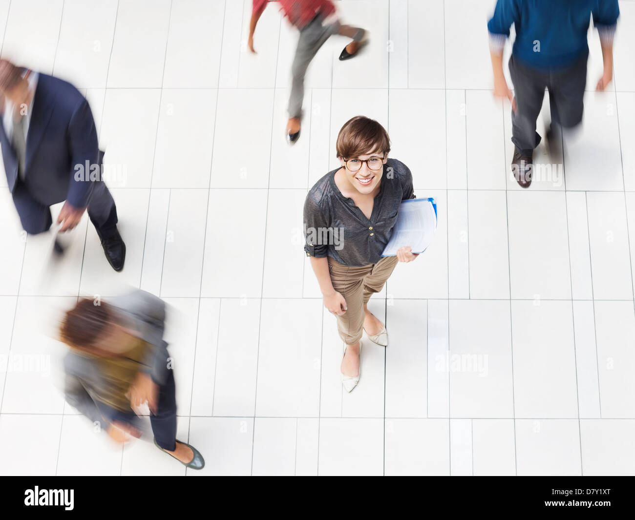 Businesswoman smiling in busy office hallway Banque D'Images