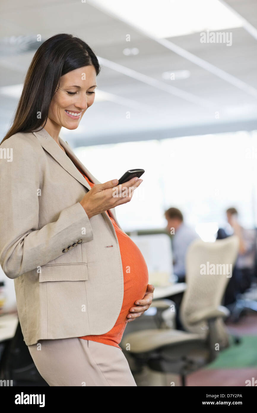 Pregnant businesswoman using cell phone Banque D'Images