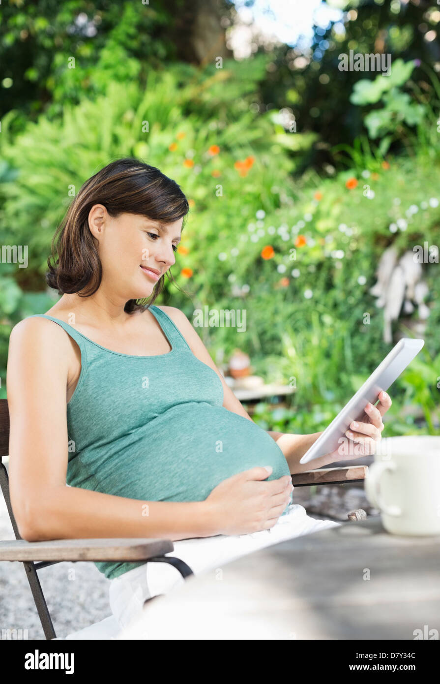 Pregnant woman using tablet computer outdoors Banque D'Images