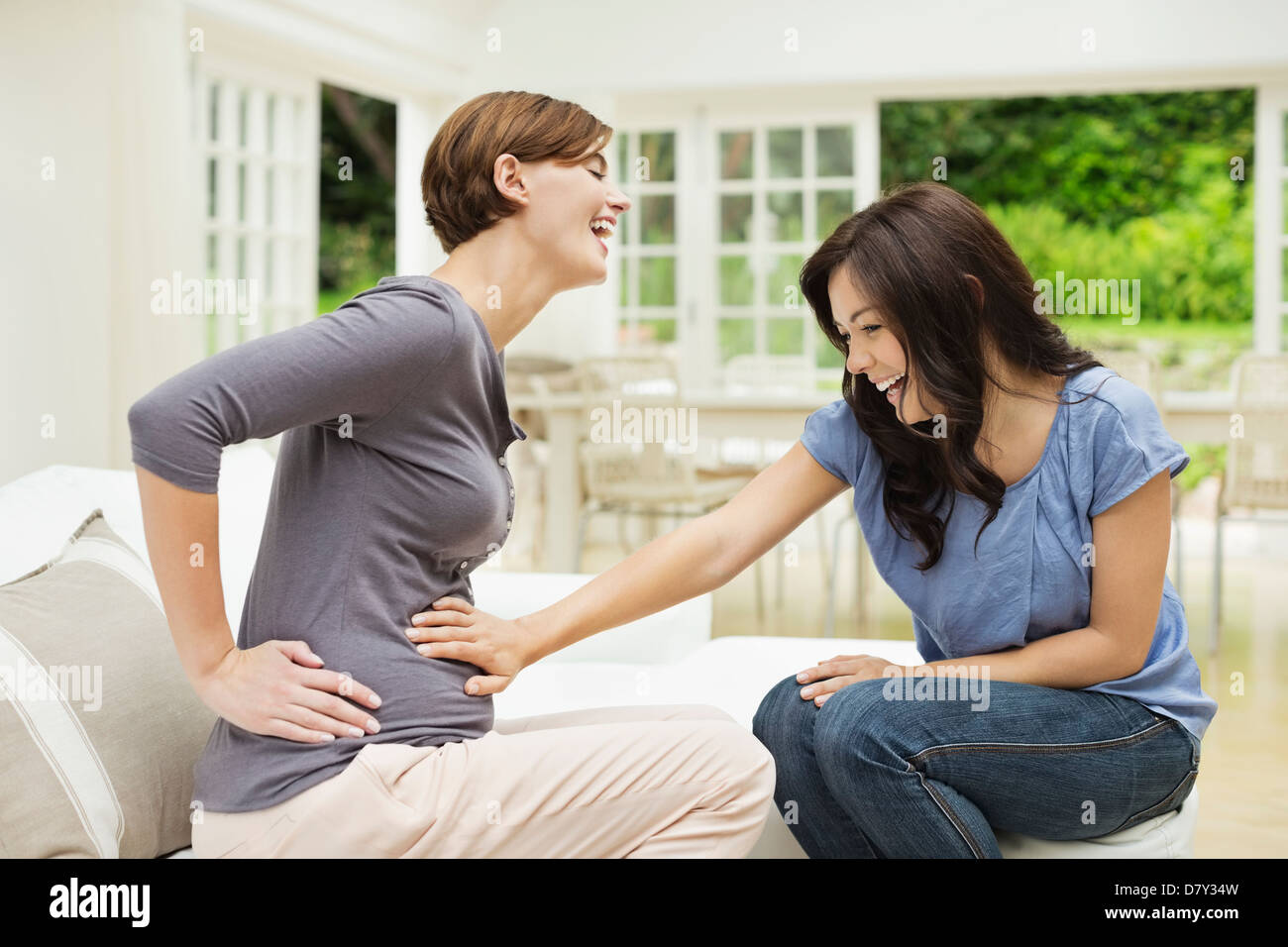 Woman holding pregnant friend's belly Banque D'Images