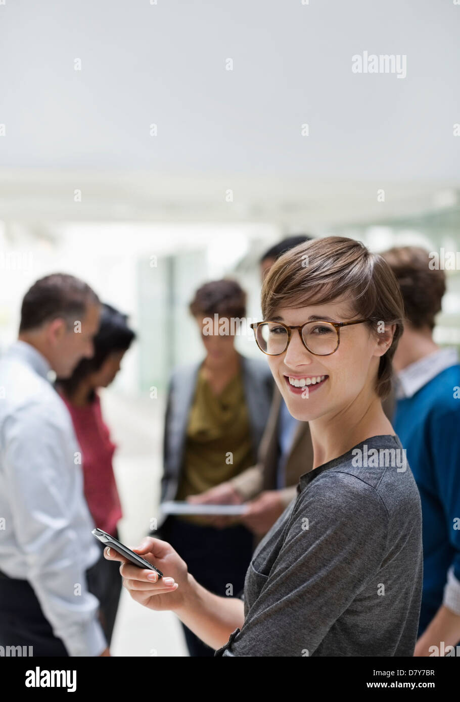 Businesswoman using cell phone in meeting Banque D'Images