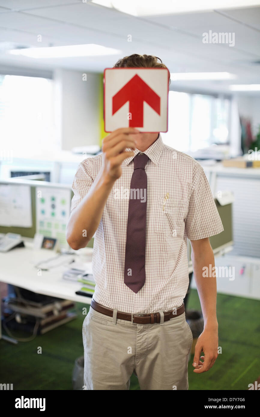 Businessman holding arrow sign in office Banque D'Images